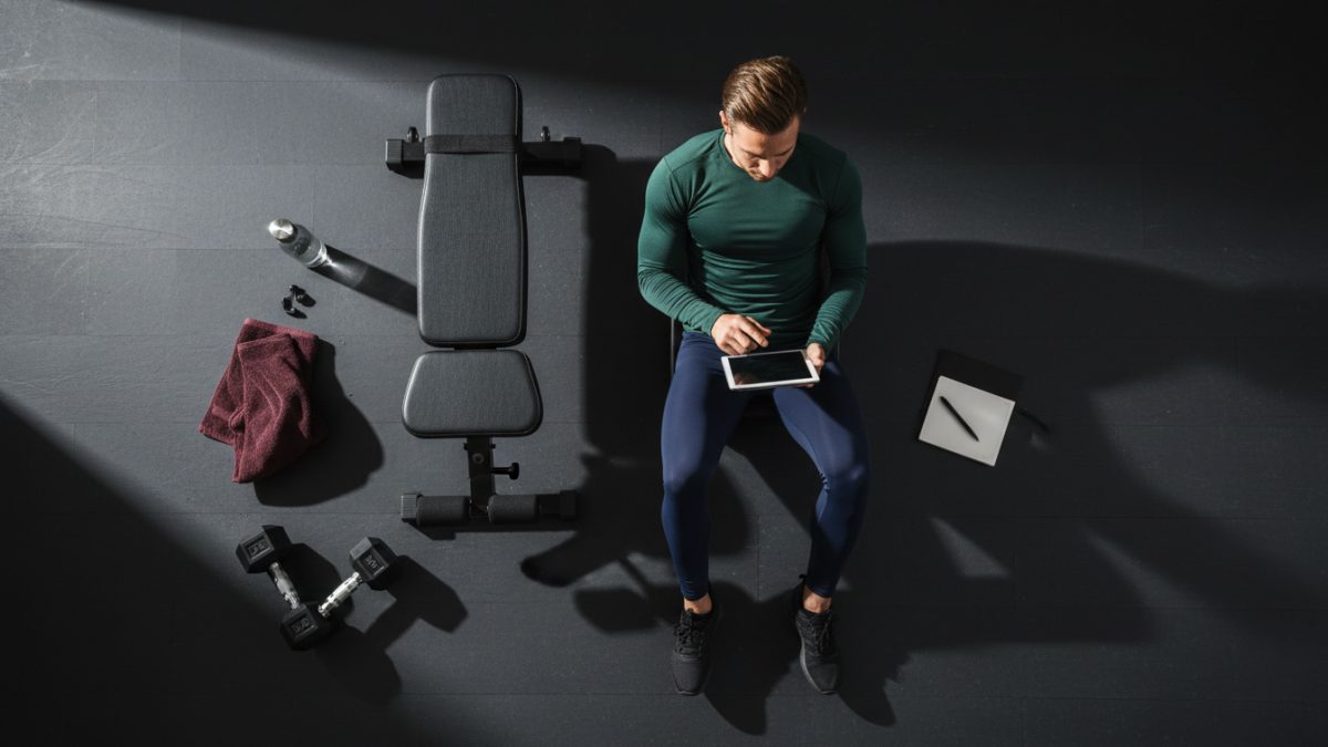 Lifter reviewing their body recomposition workout plan next to dumbbells